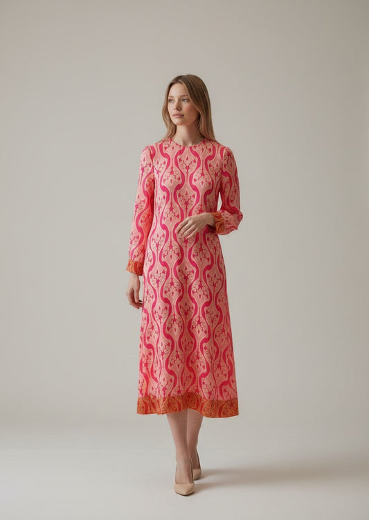 The Round Rack pink geometric Hayes midi dress with long sleeves and a crew neck, worn by a model holding a teacup.